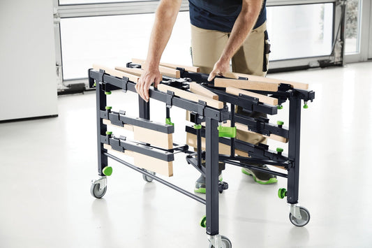 Festool STM 1800 mobiler Säge- und Arbeitstisch mit Holzplatten und Rollen, Mann positioniert Plattenmaterial