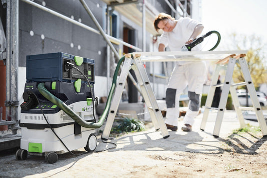 Festool SYS-PST 1500 Li HP PowerStation mit Saugschlauch auf Baustelle, Handwerker mit Schleifer auf Gerüst