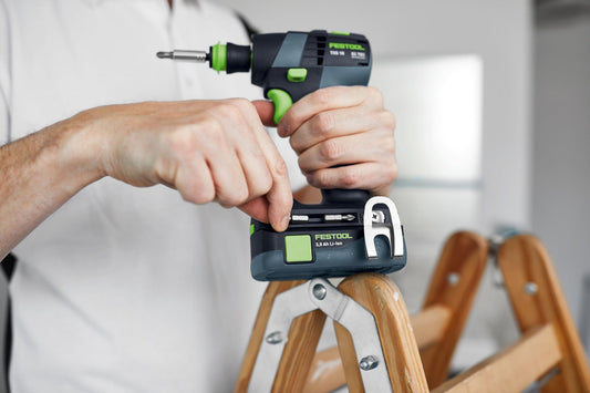 Festool TXS 18-Basic Akku-Bohrschrauber in Anwendung mit 3,0 Ah Li-Ion Akku in Hand über Holzleiter