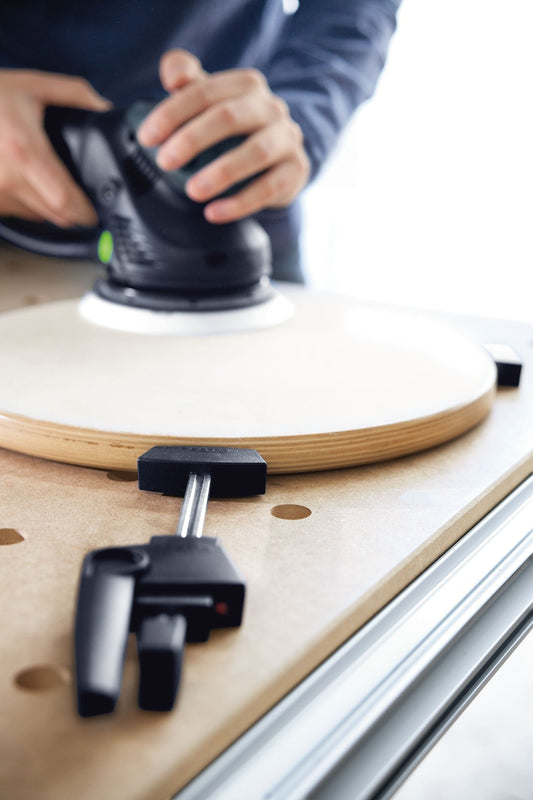 Festool MFT/3 Multifunktionstisch beim Schleifen mit Exzenterschleifer, Spannelemente und Aluprofil sichtbar.