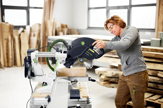 Handwerker bedient Festool Kapp-Zugsäge mit Kreissägeblatt beim Sägen von Holzwerkstück in Werkstatt