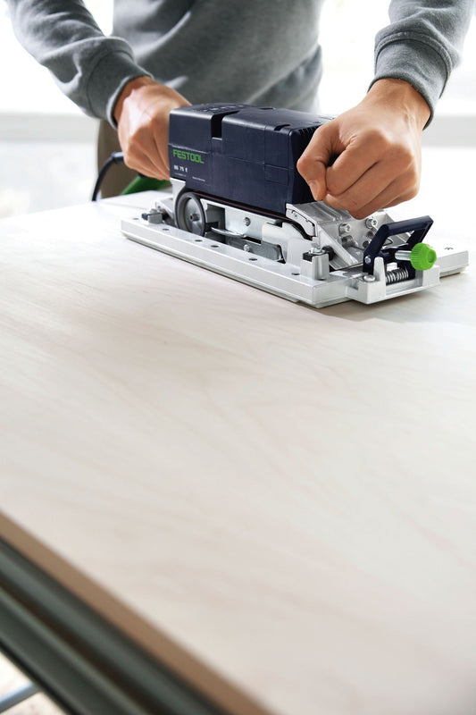 Festool BS 75 E Bandschleifer wird mit beiden Händen auf heller Holzoberfläche angewendet, zeigt Schleifplatte und grünen
