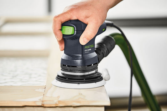 Festool ETS 125 REQ-Plus Exzenterschleifer in Anwendung auf Holzwerkstück, grüner Absaugschlauch sichtbar