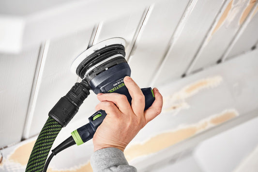 Festool Schleifteller mit Klettbelag wird von Hand bei Deckenarbeiten angebracht, grün-schwarzes Design sichtbar.