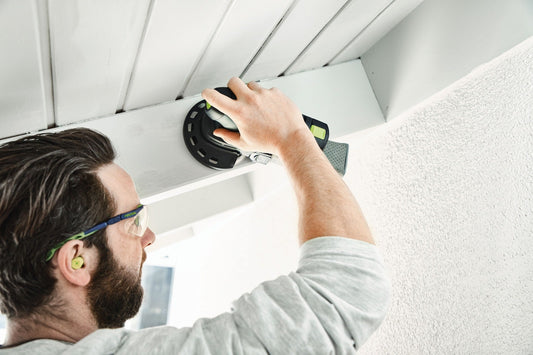 Festool Akku-Exzenterschleifer ETSC 125 beim Schleifen an Deckenplatte, Handgriff und Schleifteller sichtbar