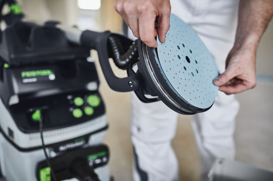 Festool Granat Schleifscheibe mit StickFix-Klettsystem in der Hand, Schleifteller im Hintergrund