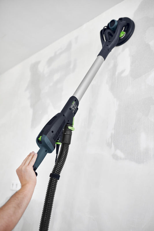 Festool PLANEX LHS 2-M 225 EQ Langhalsschleifer wird von Hand an Wand gehalten, Schleifteller oben sichtbar