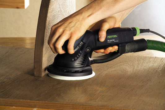 Festool ROTEX RO 150 FEQ Exzenterschleifer beim Schleifen von Holzoberfläche mit weißem Schleifteller