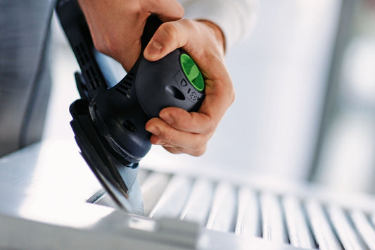 Festool RO 90 DX Deltaschleifer mit grünem Schleifteller und Schleifblatt auf Holzoberfläche