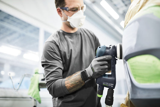 Festool Exzenterschleifer mit Schleifscheibe beim Feinstschliff auf weißem Werkstück, Arbeiter mit Schutzausrüstung