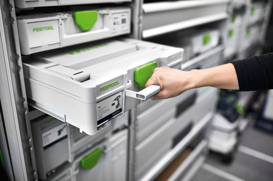 Festool Systemakkus in weißem Systainer-Regal mit grünem FESTOOL-Logo, Hand entnimmt Akku aus Halterung