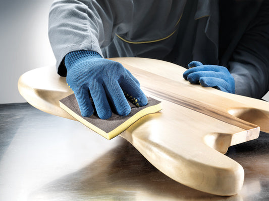 Anwendung der sia 7983 siasponge flex Pads beim Schleifen einer Gitarrenkorpus-Oberfläche – ideal für präzises Handschleifen von Holz.